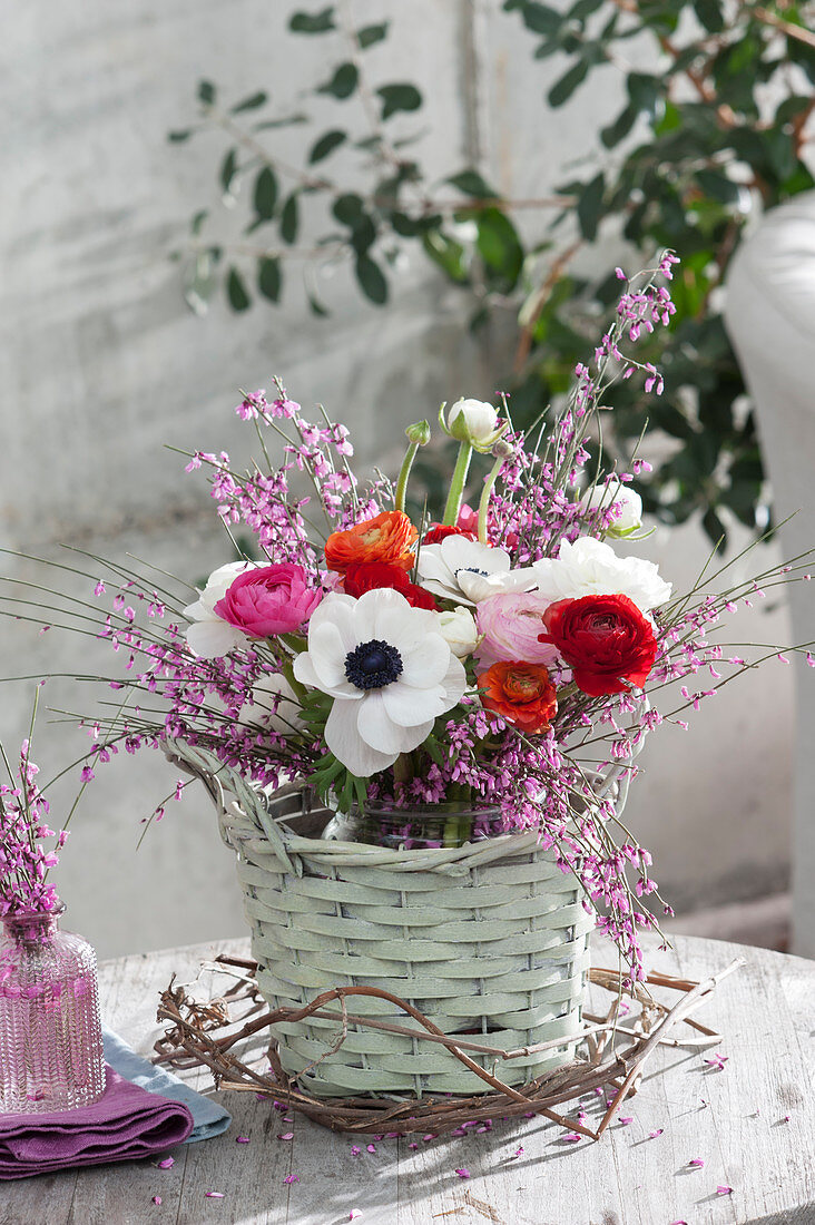 Spring bouquet of anemones, ranunculus, and broom in a basket