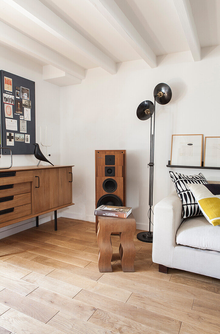 Weißes Sofa, Stehlampe, Lautsprecher, Retro Sideboard und Pinnwand in Loft-Wohnung