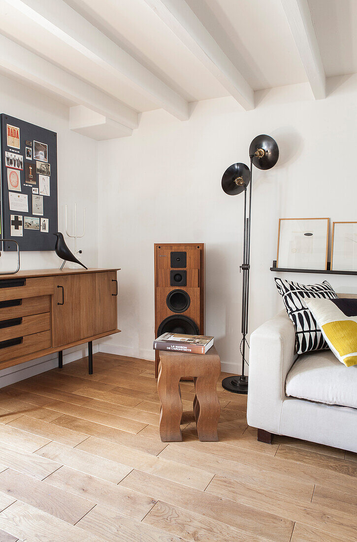 White sofa, floor lamp, speakers, retro sideboard and pinboard in a loft