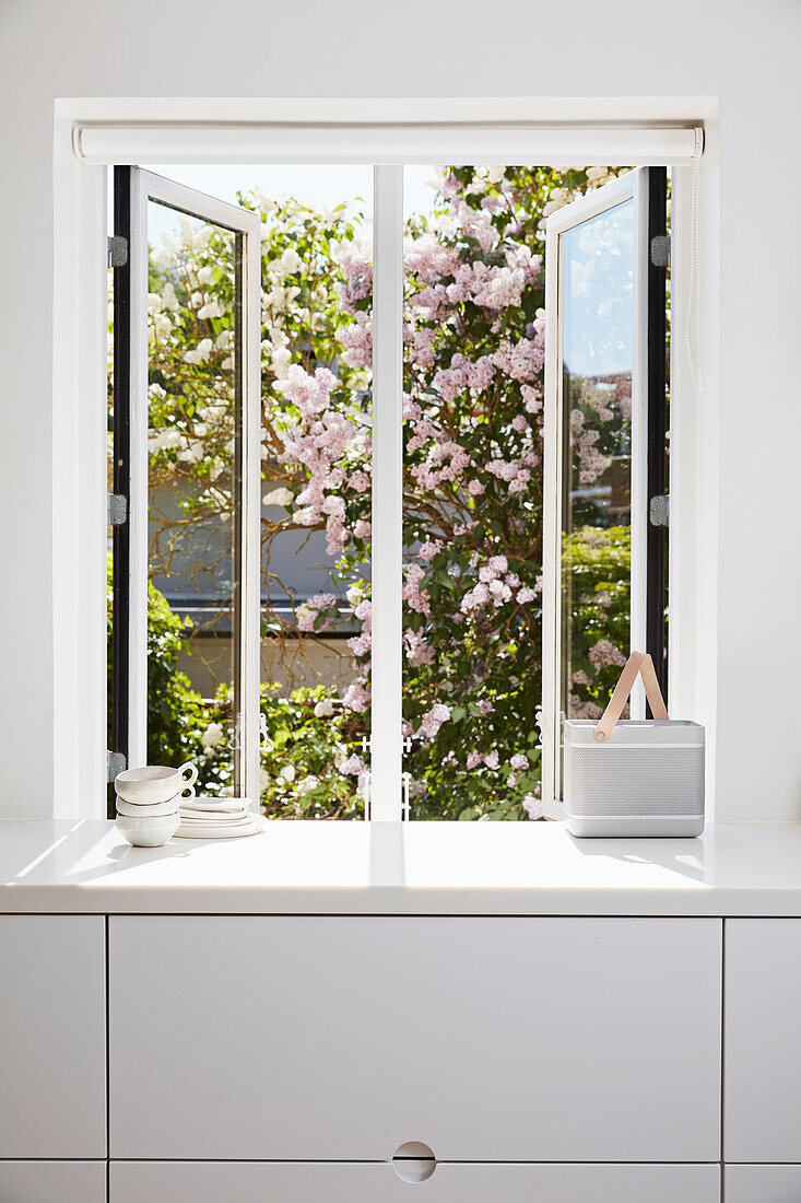 Fenster mit Gartenblick über weißer Küchenzeile