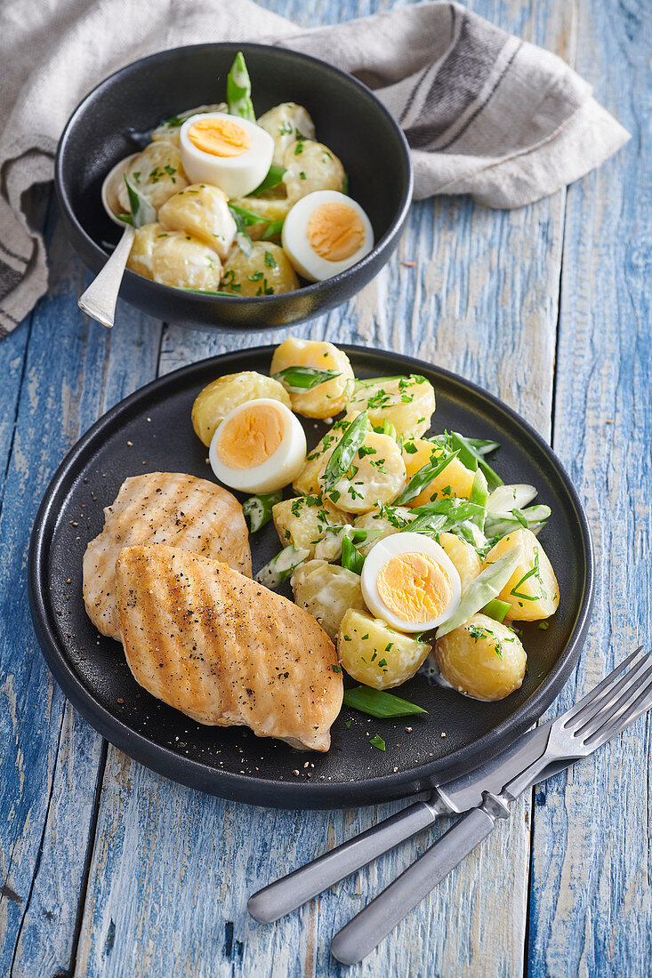 Kartoffelsalat mit Frühlingszwiebeln und gekochten Eiern dazu Hühnchensteak