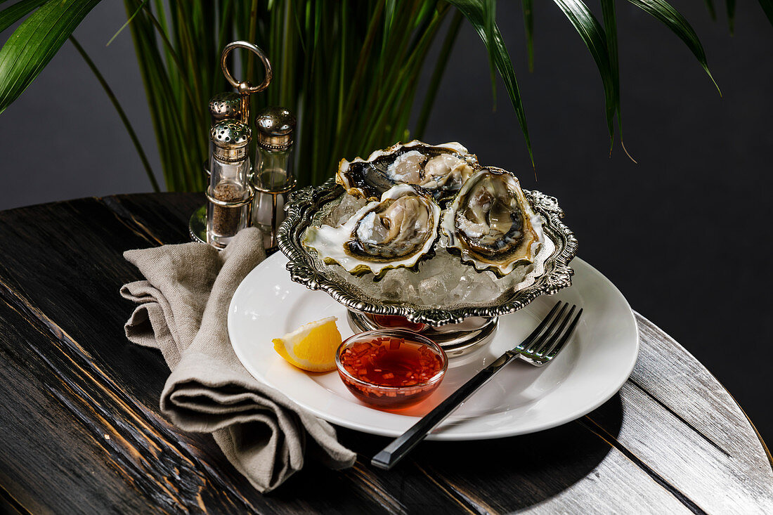 Fresh oysters on ice in silver bowl and sauce