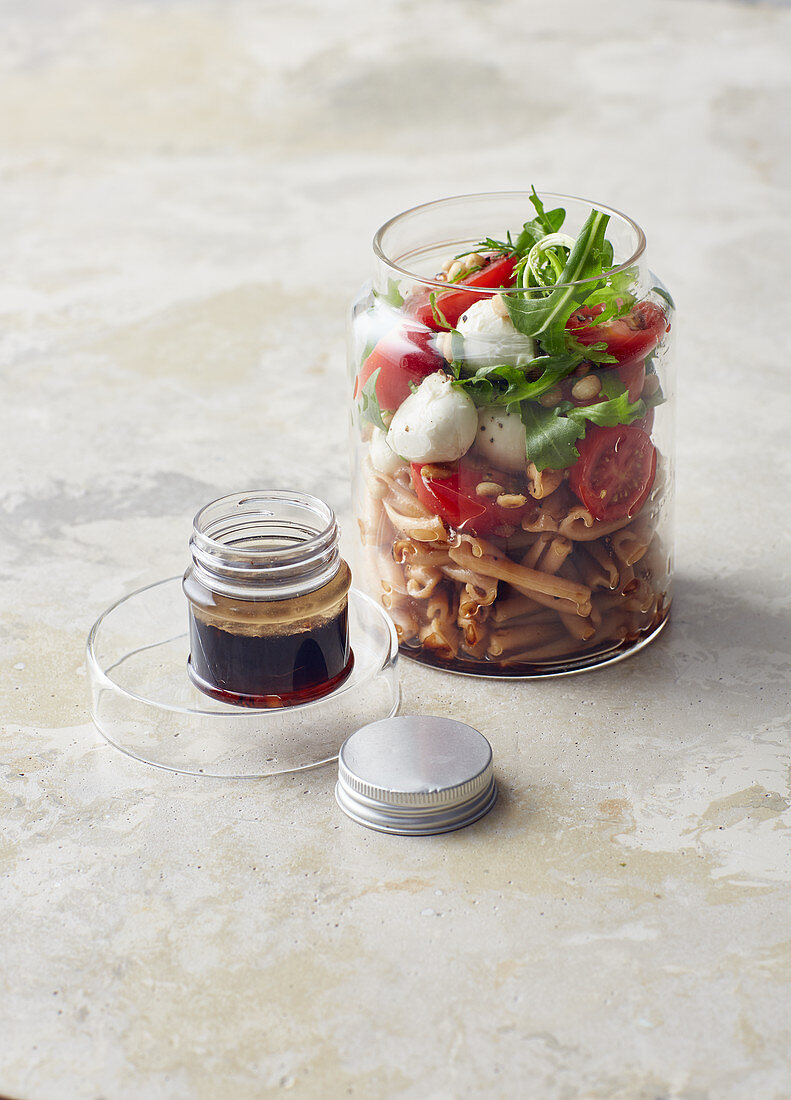 Pasta salad in a jar with rocket, mini mozzarella and tomatoes