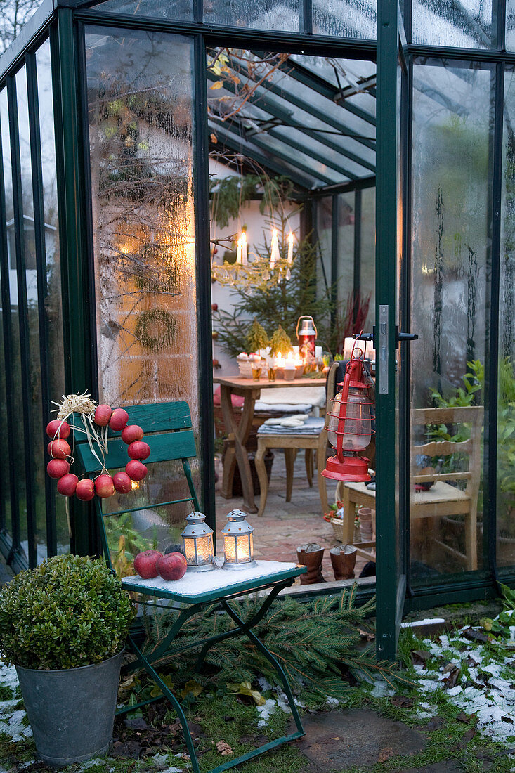 Wreath of apples on chair outside festively decorated conservatory