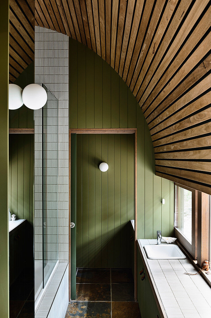 Schmales Badezimmer mit grüner Holzverkleidung und gebogener Holzdecke