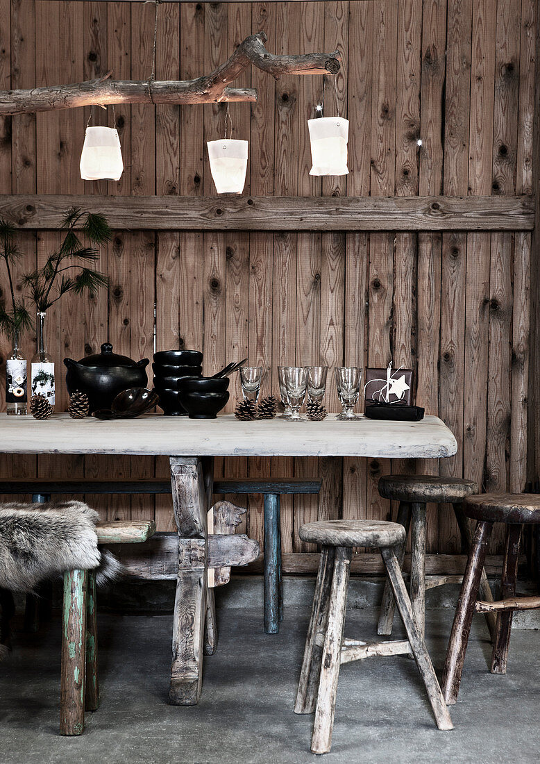 Antique wine glasses and black crockery on table in front of rustic board wall