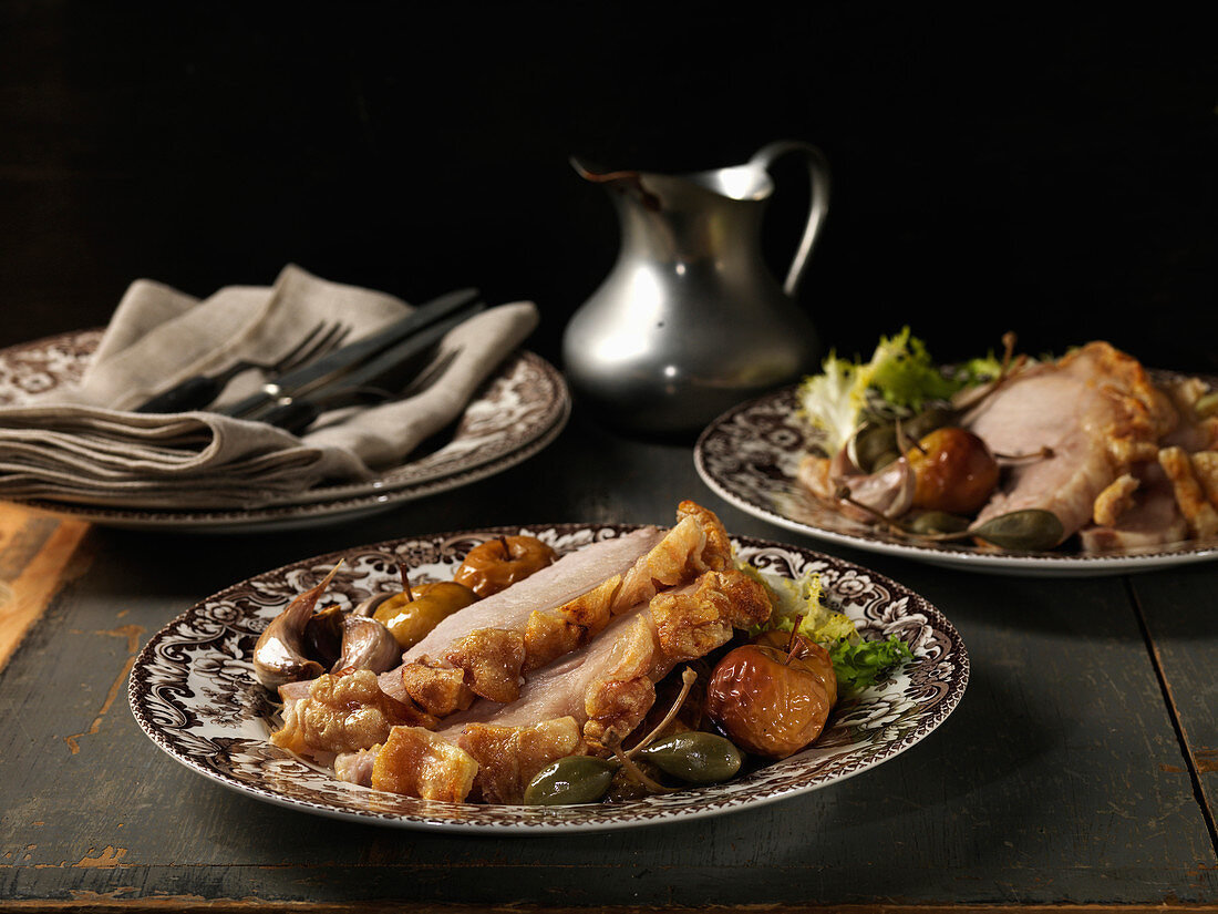 Plated Roast Pork Slices with Crust, Roasted Apples, Caper Berries and Garlic Cloves