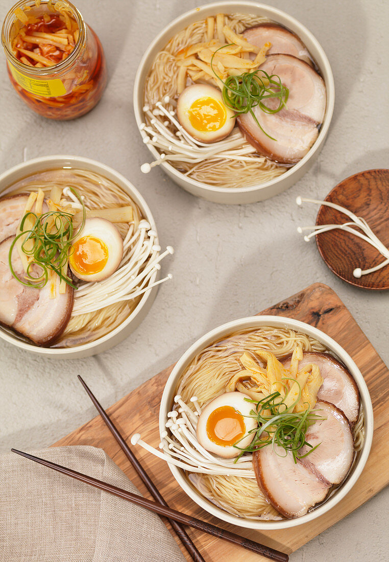 Bowls of Ramen Noodle Soup with Seasoned Egg, Pork, Enoki Mushrooms and Green Onions