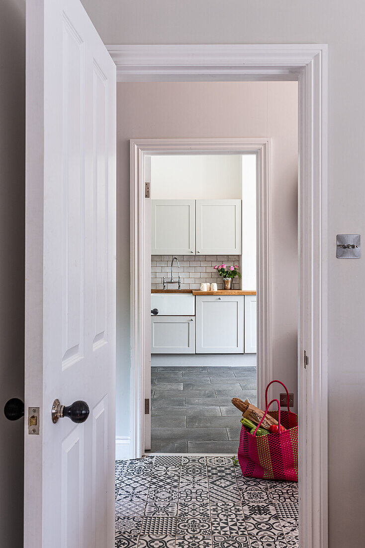 looking through an open coffered door across the hallway into the kitchen