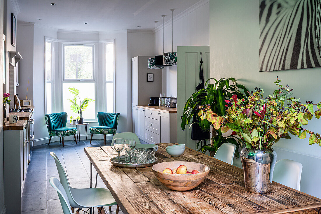 Wooden dining table in the kitchen with retro armchairs in the bay window