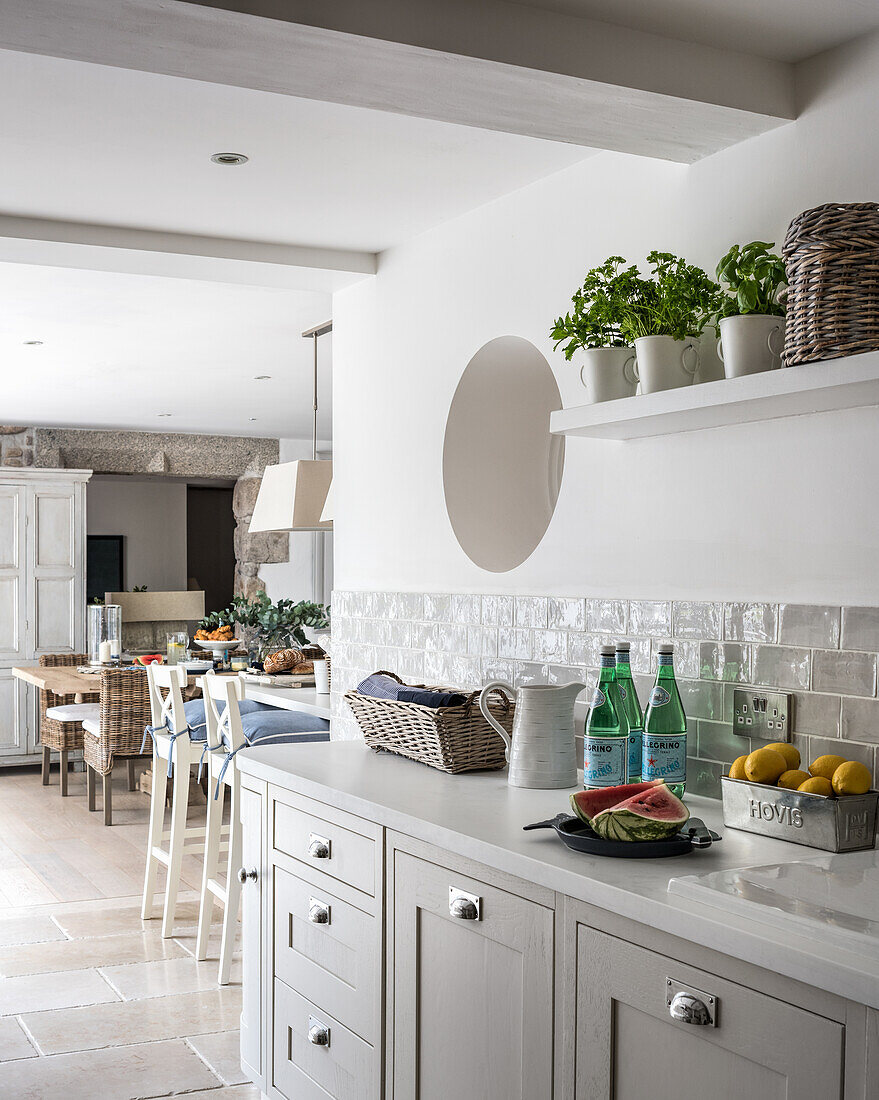 Wall tiles in spacious kitchen diner with limestone floor tiles and porthole window