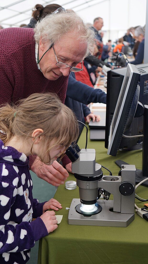 Child looking through a microscope at a science fair