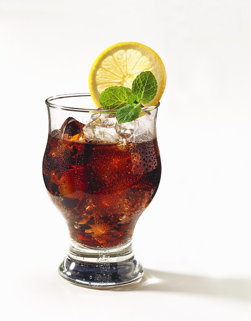 A glass of Cola with ice, decorated with mint & lemon slice