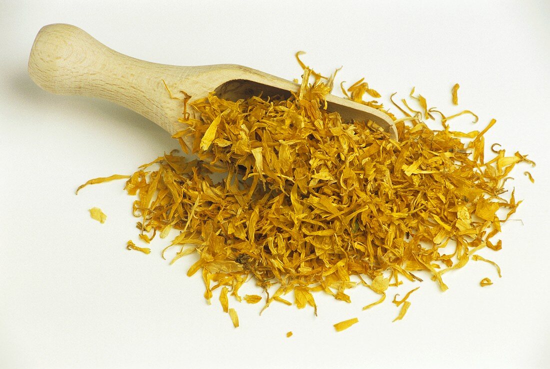 Dried marigold flowers on wooden scoop