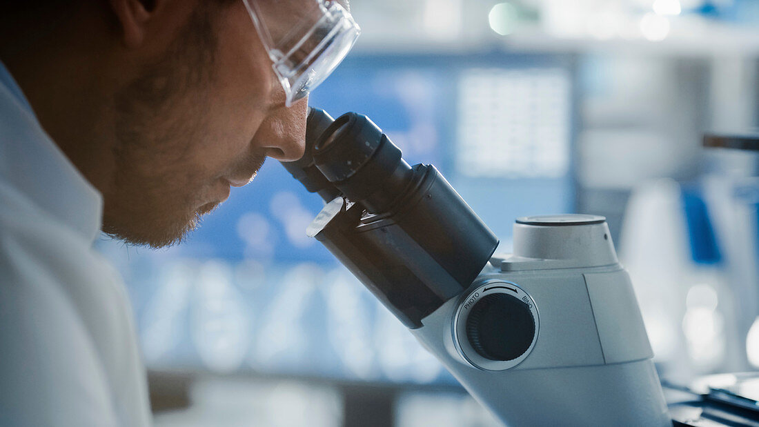 Scientist looking into microscope