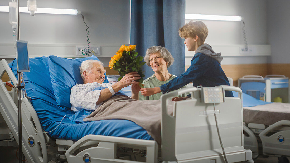 Wife visiting elderly man on hospital ward