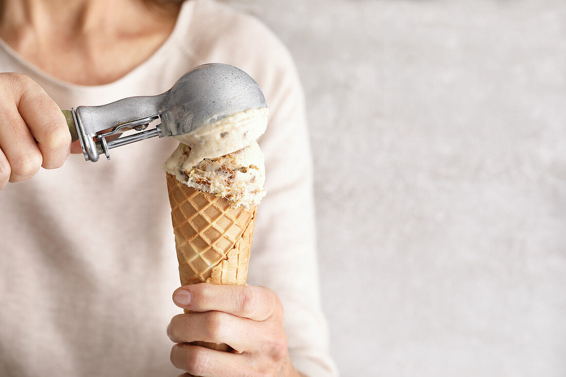Woman squeezes ice cream scoops on an ice cream cone