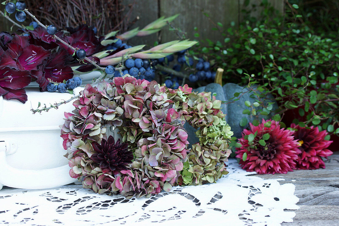 Autumn arrangement of hydrangea and dahlia wreaths, blue-green pumpkin, branch of sloes and gladioli