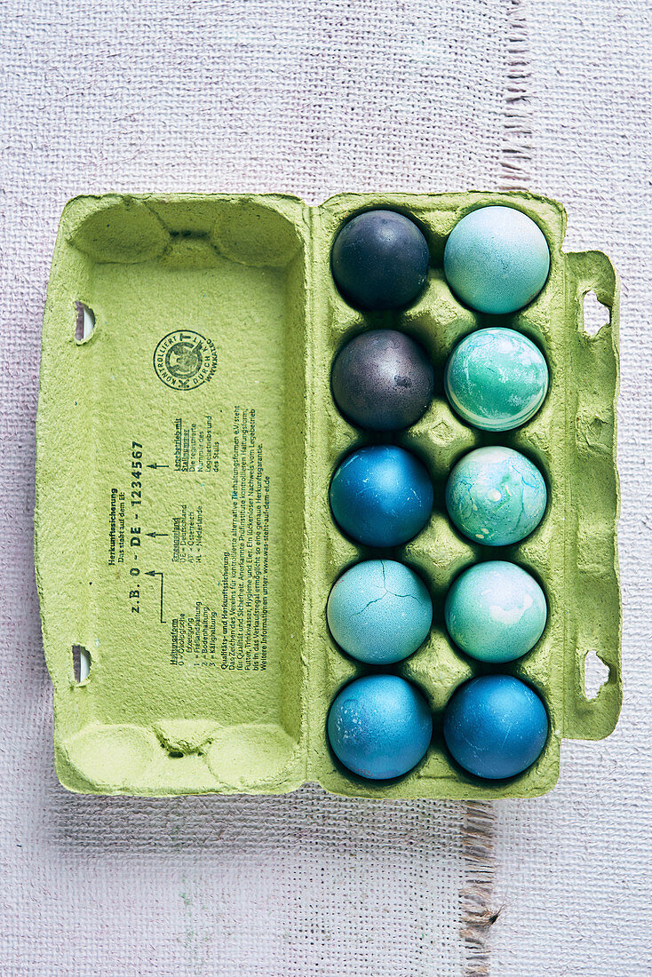 Colorful dyed Easter eggs in shades of blue in an egg carton