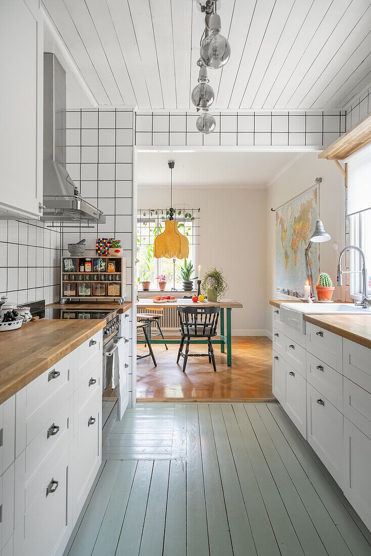 View through white kitchen with grey floorboards into dining room