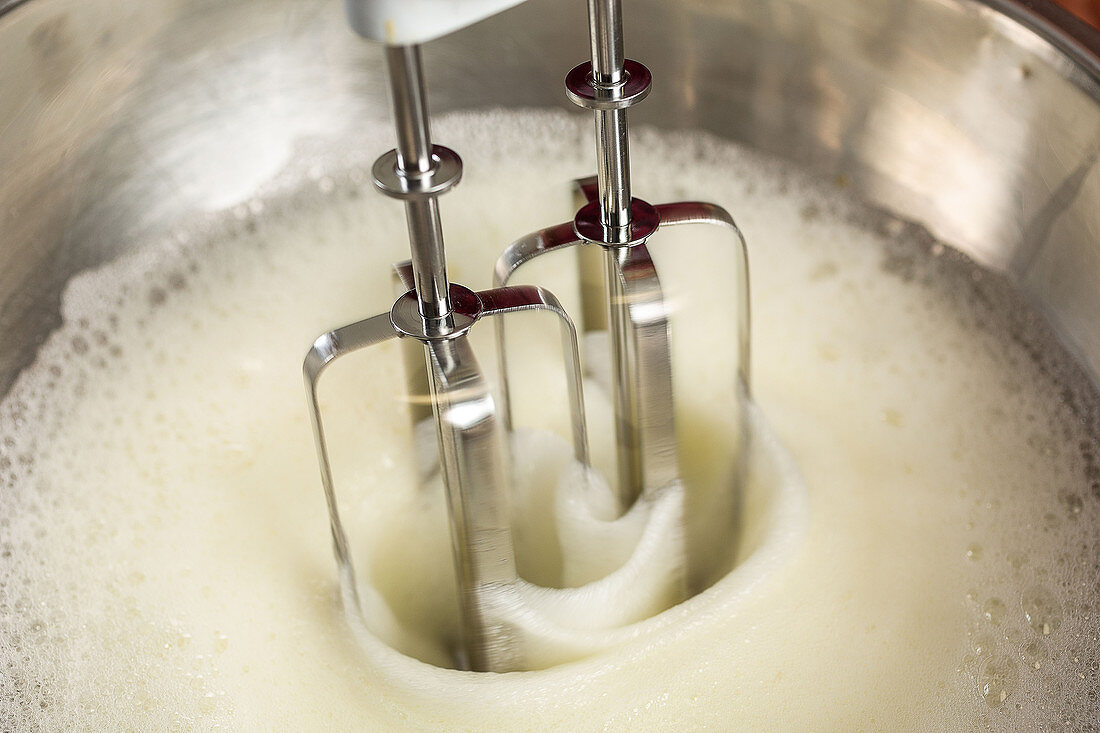 Beating egg whites with a hand mixer until stiff