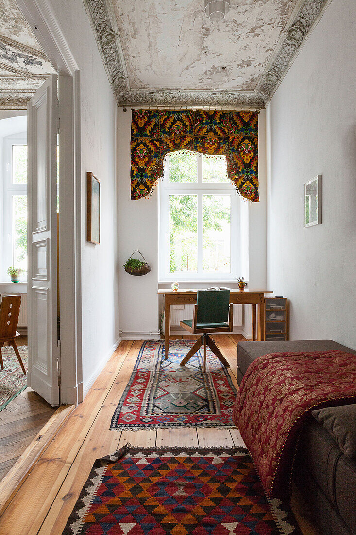 Bett und Schreibtisch im Altbau-Wohnzimmer mit Stuckdecke