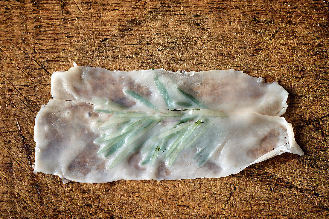 A thin slice of lardo with rosemary