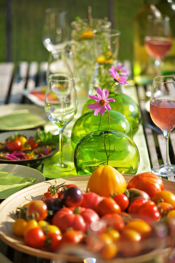 Verschiedene frische Tomaten auf sommerlich gedecktem Gartentisch