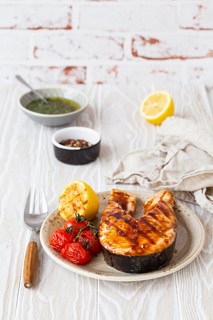 Grilled salmon steak glazed with teriyaki sauce, tomatoes and lemon