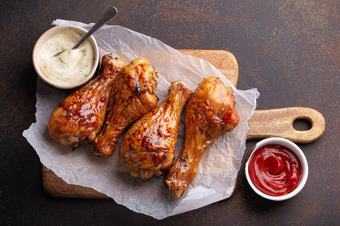 Roasted chicken drumsticks on paper, ketchup and mayonnaise