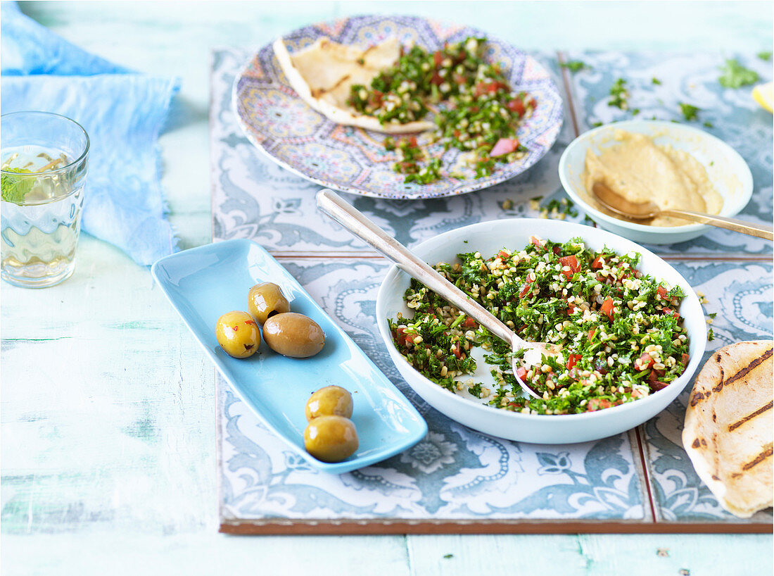 Fladenbrot, Taboulé, Hummus und Oliven auf Fliesen