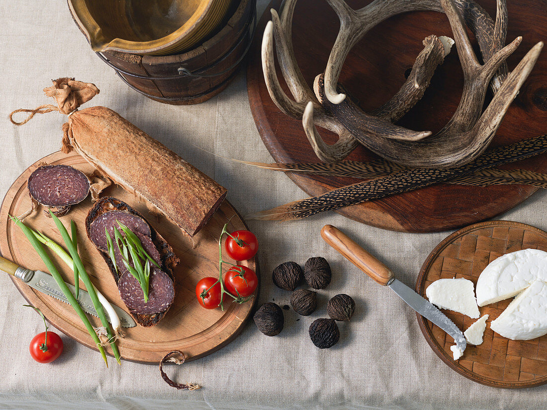 Overhead View of Charcuterie On Wood Boards With Jug, Wooden Bucket, Feathers And Antlers