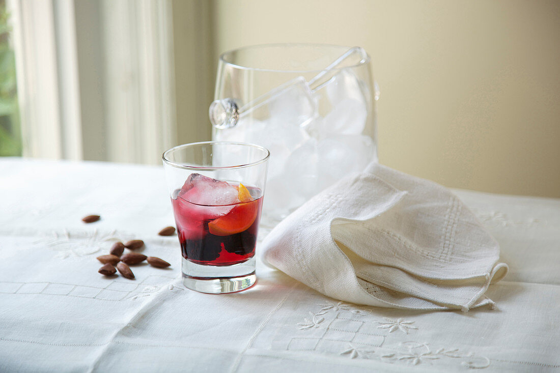 Cocktail With Ice Bucket, Almonds and Cloth Napkin On Table Beside Window