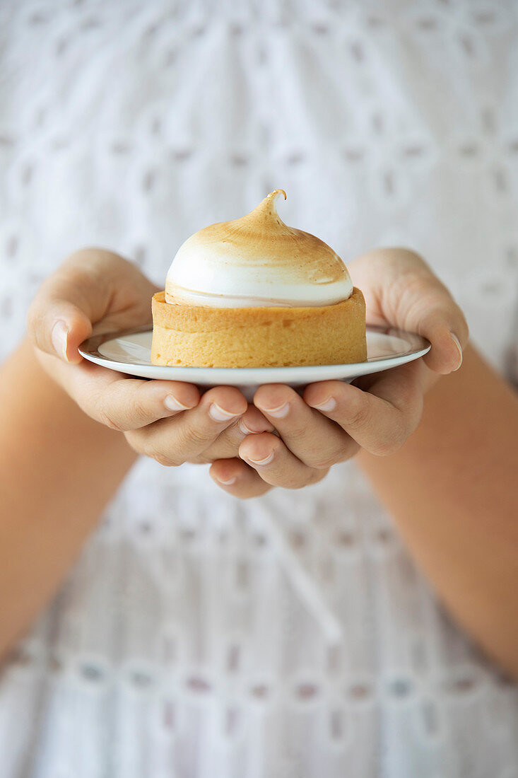 Lemon Meringue pie being held in a girls hands