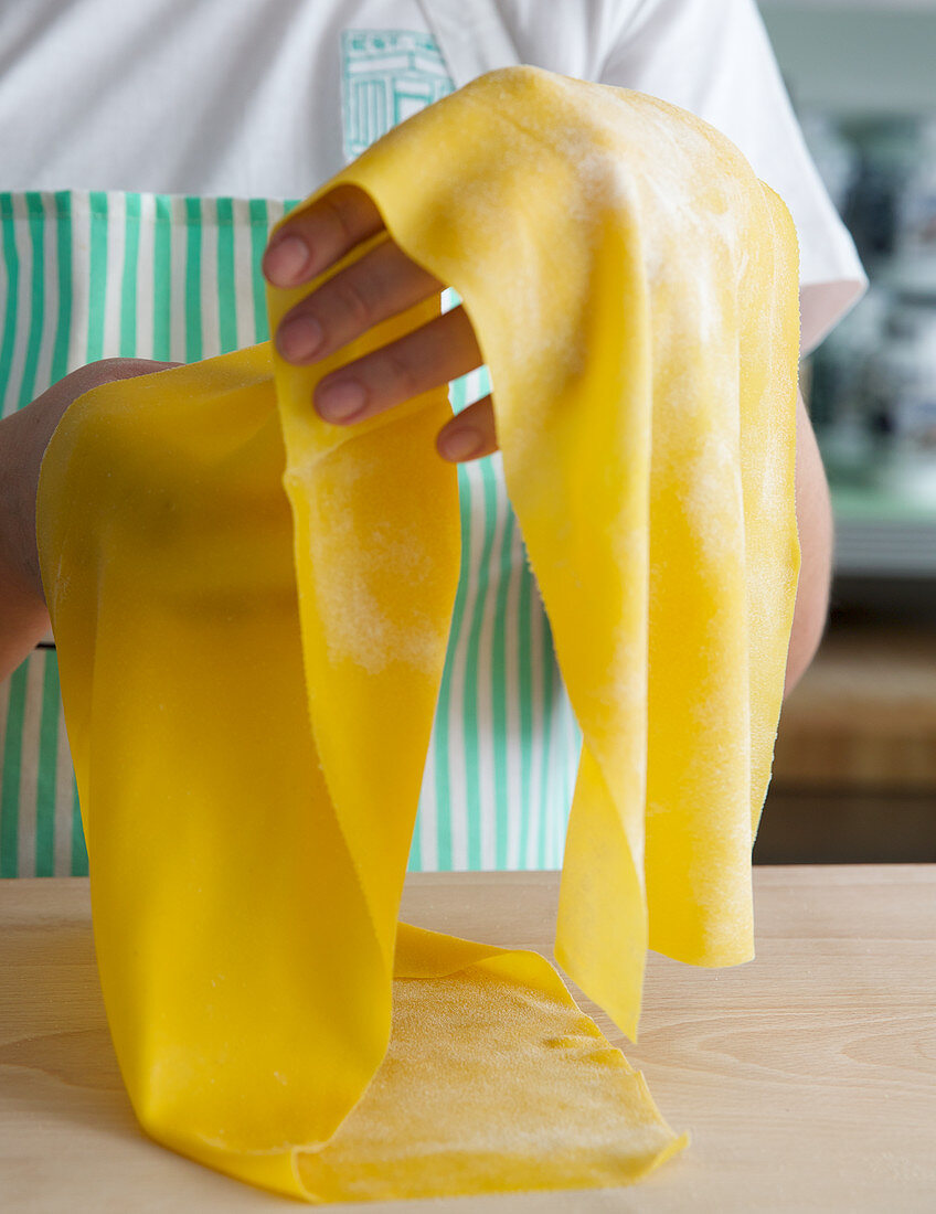 Hands holding homemade pasta sheets