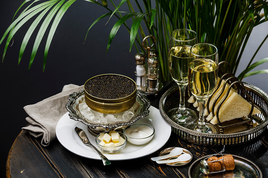 Schwarzer Kaviar auf Eis in Silberschale dazu Champagner und Brot