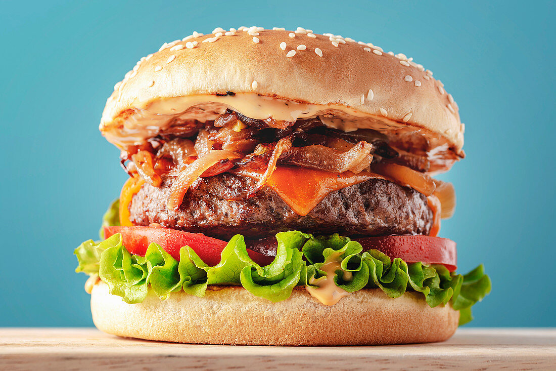 Classic hamburger with lettuce, tomatoes, cheddar cheese and caramelized onions