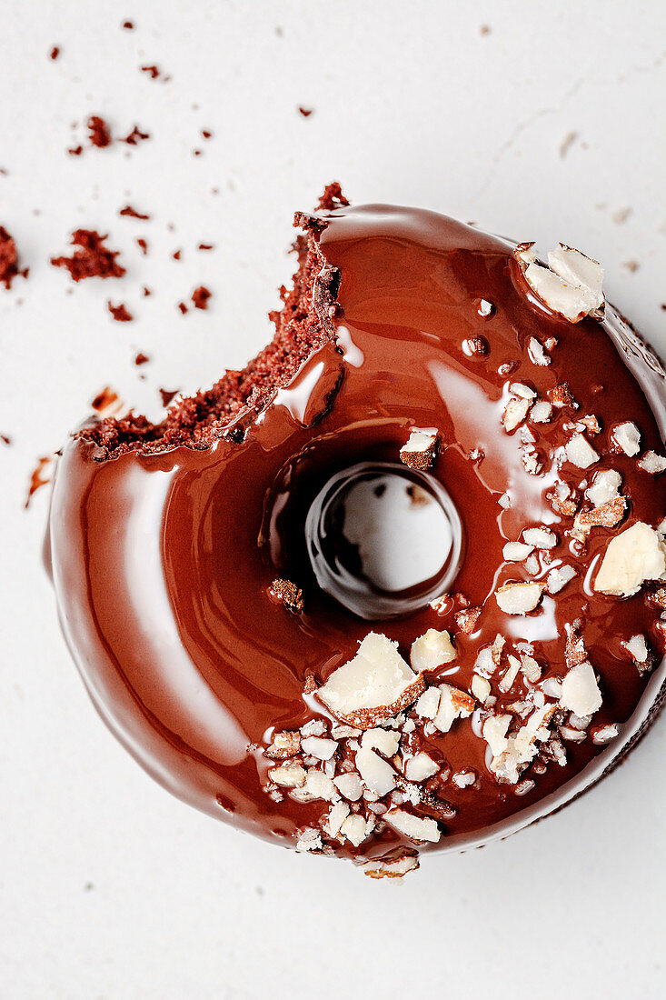 Angebissener Schokoladendonut mit Schokoglasur und Mandeln
