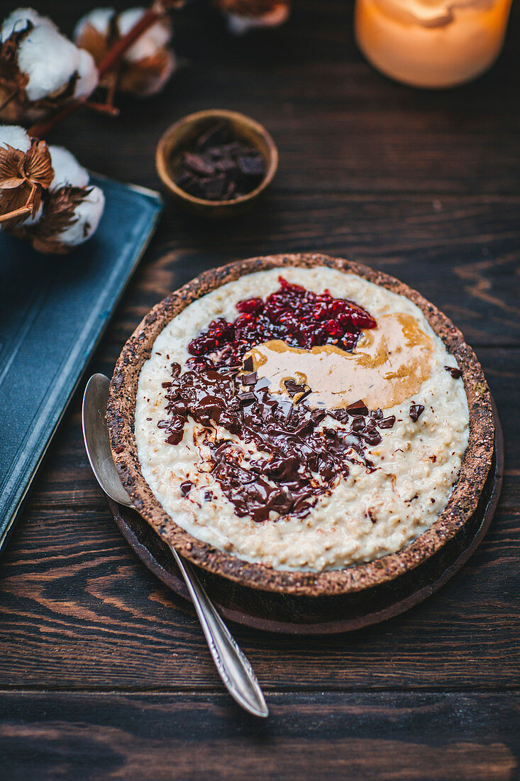 Oatmeal topped with raspberry jam, dark chocolate and hazelnut butter