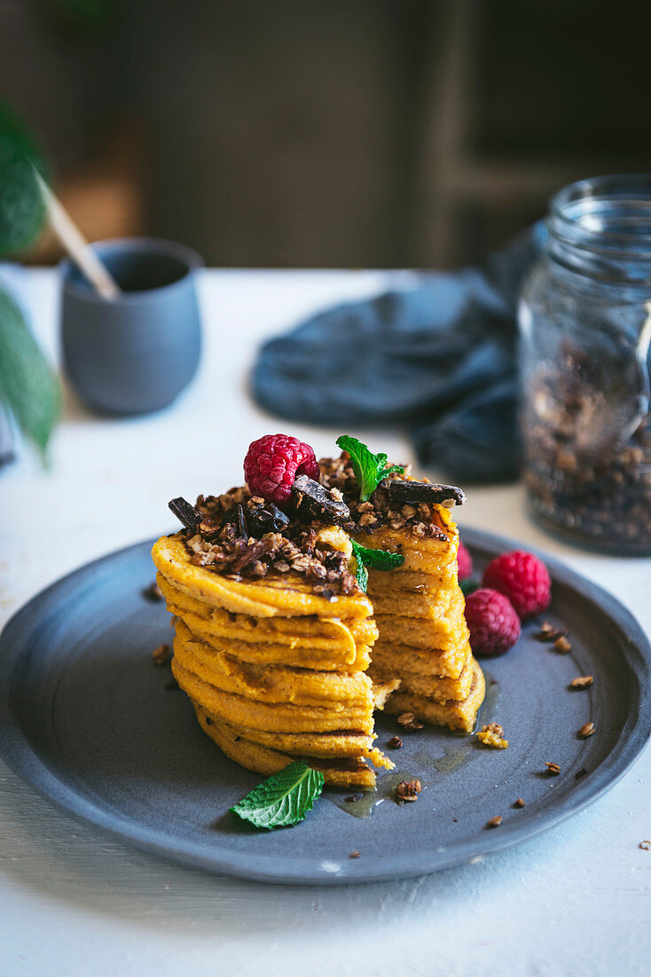 Stacked pumpkin pancakes with granola and raspberries
