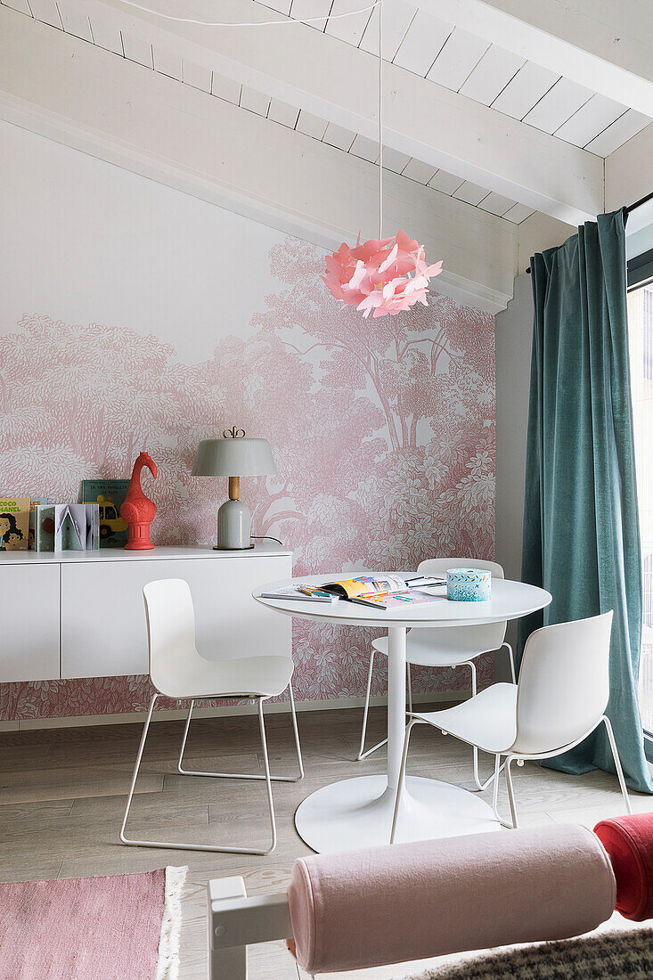 Weißer Tisch mit Stühlen und Hängeboard vor rosa Tapete im Mädchenzimmer