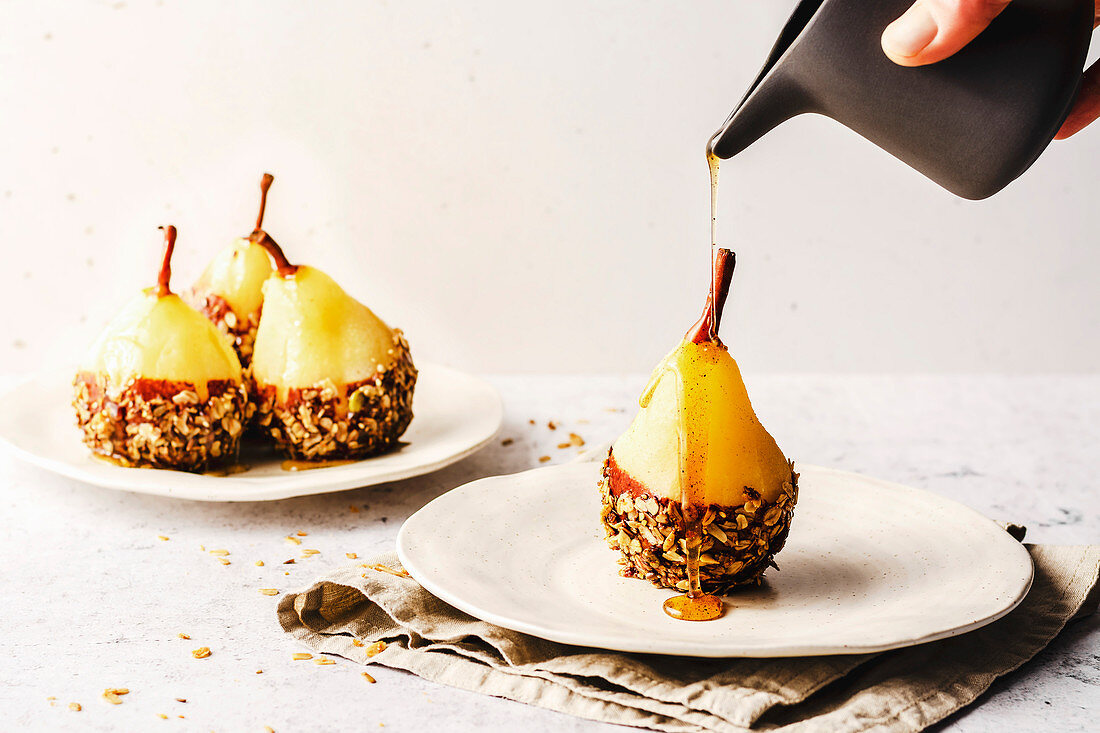 Poached pear with chocolate and granola, drizzled with syrup