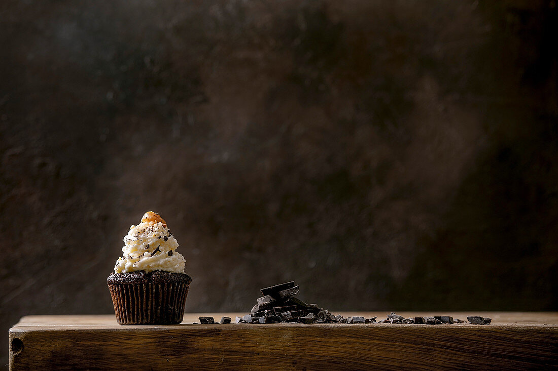 Schokoladenmuffin mit Schlagsahne und Salzkaramell vor dunklem Hintergrund