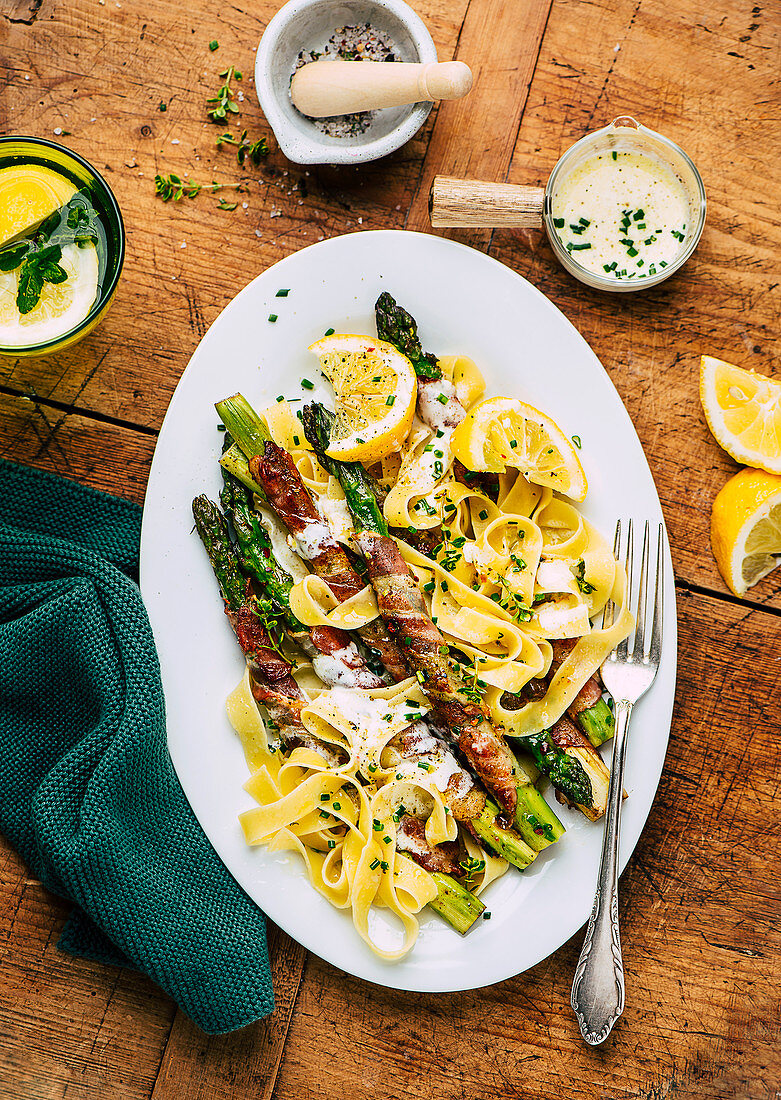 Asparagus wrapped in bacon with ribbon noodles and cheese sauce
