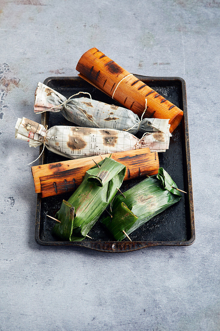 Fish wrapped in banana leaves, woodsheets or newspaper