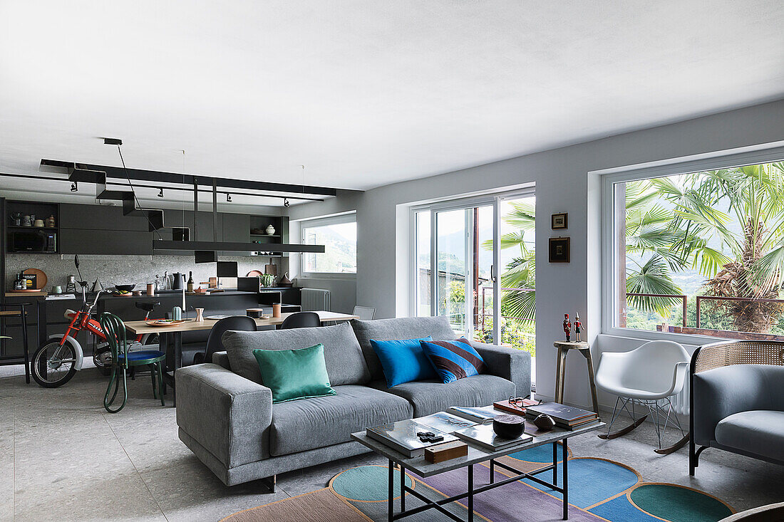 Gray upholstered sofa, dining area, and kitchen in the background in an open-plan living space