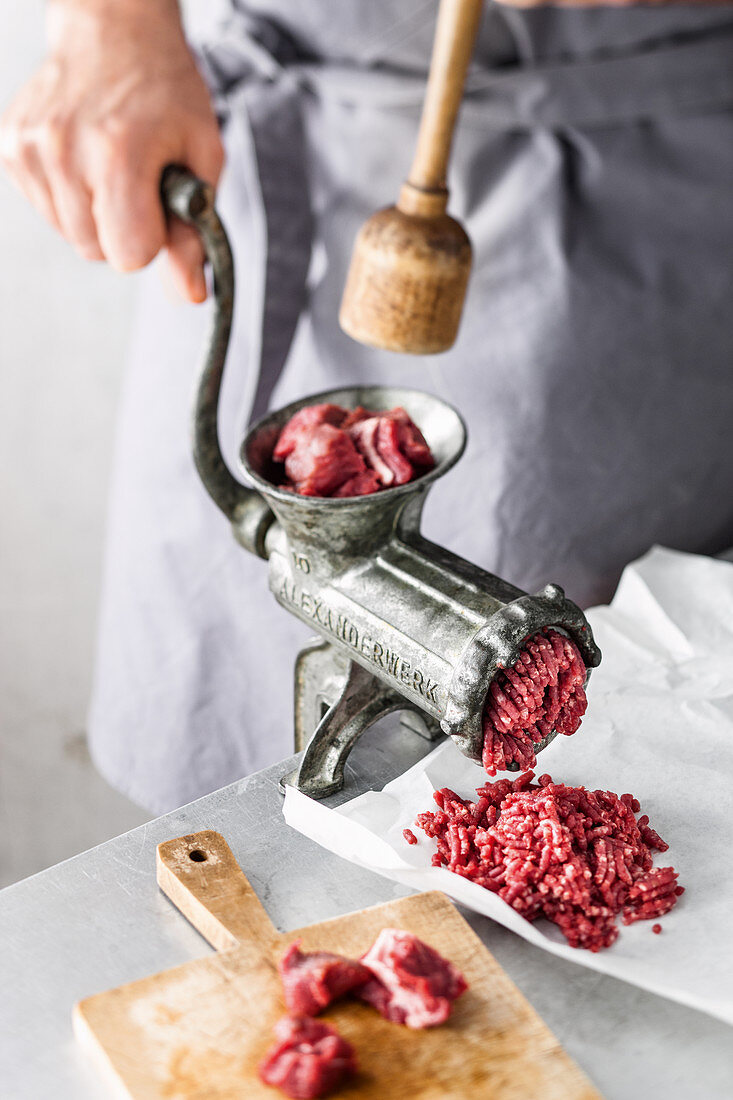 Beef is turned through a meat grinder (for beef patties)