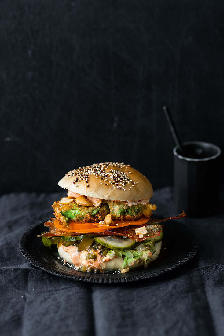 Vegan burger with fried avocado, sriracha mayonnaise and 'bacon'