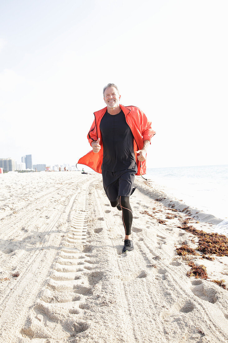 A grey-haired man jogging by the sea