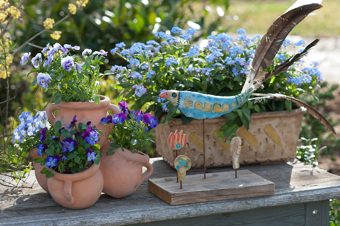 Spring arrangement with horned violets, forget-me-nots, and a ceramic bird
